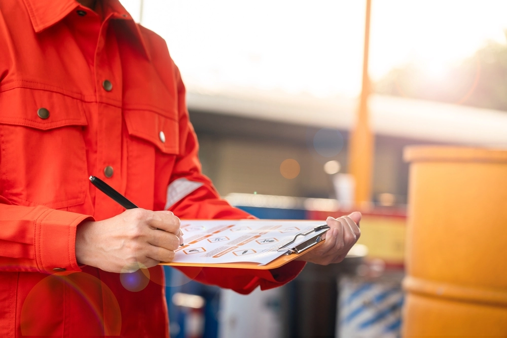 A warehouse engineer holding a hazardous material checklist